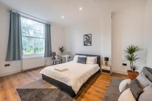 a white bedroom with a bed and a couch at Spacious Two Bedroom Apartment in Camden by London Zoo in London