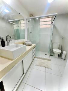uma casa de banho branca com um lavatório e um WC em Hospedagem Caminho das Praias em Niterói