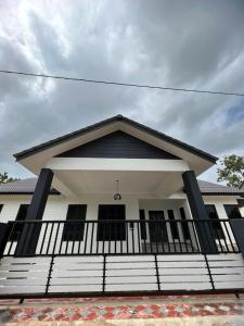 Casa blanca con porche en blanco y negro en Homestay Singgah Tamu Al Amin en Bukit Payong