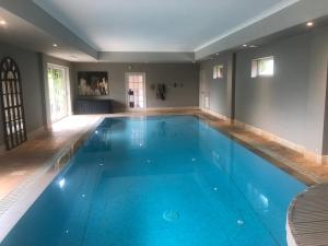 a large swimming pool with blue water in a house at Barn conversion, Henley-on-Thames in Henley on Thames