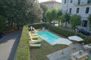 einen Pool mit Stühlen und Sonnenschirmen neben einem Gebäude in der Unterkunft Villa Lilli con piscina riscaldata in Montecatini Terme