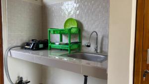 a kitchen counter with a sink and a green shelf at Danas Pandawa Homestay in Ungasan