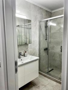 uma casa de banho branca com um lavatório e um chuveiro em Solid Residence Sea View em Mamaia