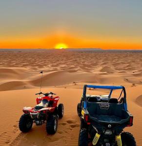 梅爾祖卡的住宿－Merzouga luxurious Camps，沙漠中的一辆公车和一辆四轮摩托车