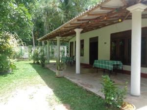 a house with a table and chairs in a yard at Green Valley Home stay in Talpe