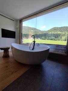 eine große Badewanne in einem Zimmer mit einem großen Fenster in der Unterkunft Exklusive Alpen Lounge Bayrischzell in Bayrischzell