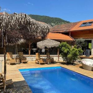 ein Resort mit einem Pool und einem Strohschirm in der Unterkunft Exklusive Alpen Lounge Bayrischzell in Bayrischzell