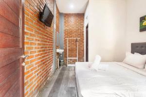 um quarto com uma cama e uma parede de tijolos em The Backyard House em Tabanan