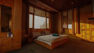 Un dormitorio con una cama en una habitación con ventanas. en BARFI MANALI, en Manali