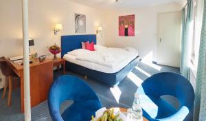 a hotel room with a bed and blue chairs at Waldhotel Bärenstein in Horn-Bad Meinberg