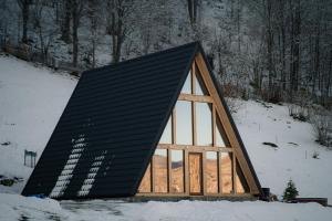a small house with a black roof in the snow at Atipic Chalet in Holda