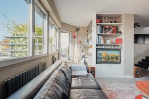 a living room with a couch and large windows at Veeve - Visual Exultation in Boulogne-Billancourt