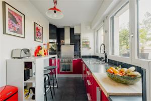 a kitchen with red cabinets and a bowl of fruit on a counter at Veeve - Visual Exultation in Boulogne-Billancourt