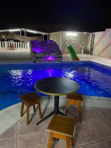 a table and two stools in front of a swimming pool at La casa de ensueño in Yeles