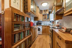 a large kitchen with wooden cabinets and bookshelves at Quaint & Cozy Cottage, Private garden & bike shed in Innerleithen