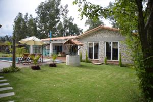 ein Haus mit einem Garten mit Pool und Sonnenschirm in der Unterkunft Casa de Campo Solar Tere in Cochabamba
