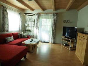ein Wohnzimmer mit einem roten Sofa und einem TV in der Unterkunft Ferienwohnung Stuiber in Haarbach