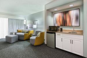 Habitación de hotel con sala de estar con TV. en Courtyard by Marriott Wilmington/Wrightsville Beach, en Wilmington