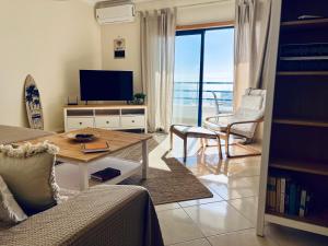 uma sala de estar com um sofá e uma mesa com uma televisão em Pérola do Algarve em Quarteira