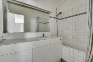 ein weißes Badezimmer mit einem Waschbecken und einem Spiegel in der Unterkunft The Heights of Saint-Cloud in Saint-Cloud
