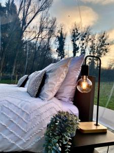 a bed with pillows and a table with a lamp at La bulle du Bon'Heure in Somme-Leuze