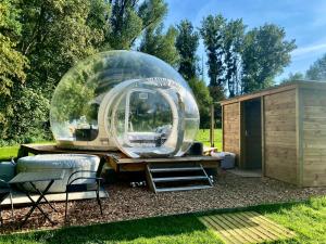 una vista exterior de una casa en la cúpula con mesa y sillas en La bulle du Bon'Heure en Somme-Leuze