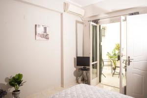 a white bedroom with a bed and a television at Historical center small diamond in Kalamata
