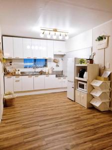 a kitchen with white cabinets and a wooden floor at Jamsil Heaven in Seoul