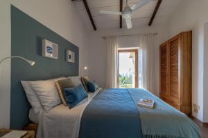 1 dormitorio con 1 cama azul y ventilador de techo en Villetta indipendente sul Mare, en Monte Argentario