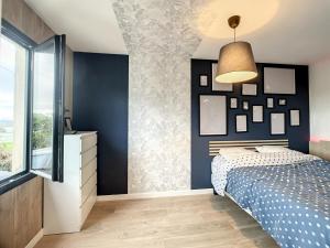 um quarto com paredes azuis, uma cama e uma janela em La Pommedepin Ravissante maisonnette avec jardin em Plouescat