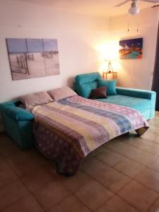 a bedroom with a couch and a bed with a blanket at Vero House TERRAZA DE LA PAZ in San Miguel de Abona