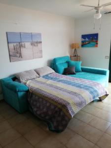 een slaapkamer met een blauwe bank en een bed bij Vero House TERRAZA DE LA PAZ in San Miguel de Abona