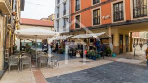 eine Straße mit Tischen, Stühlen und Sonnenschirmen in der Unterkunft Loft Arco de los zapatos,Casco histórico Oviedo in Oviedo + 30 Fotos