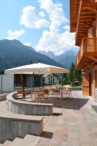 a patio with tables and chairs and an umbrella at Lumen in Falcade