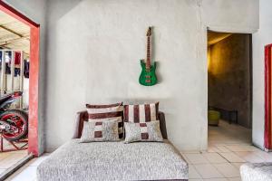 a bedroom with a bed and a guitar on the wall at OYO 90799 Griyo Sonia in Surabaya