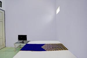 a room with a bed and a desk with a laptop at OYO Life 92937 Kost Putri Sarkara Syariah in Banyuwangi