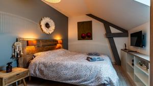 una camera da letto con un letto e una televisione di La Maison d'Ernest - Climatisée - Circuit DIJON PRENOIS a Prenois Altre 96 foto