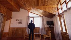 una persona parada en una habitación mirando por una ventana en BARFI MANALI, en Manali