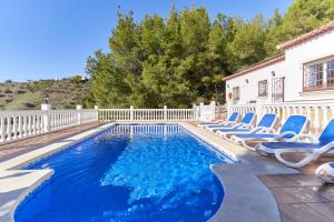 a swimming pool with lounge chairs next to a house at Villa Thomas in Frigiliana