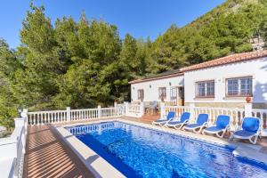 a swimming pool with blue chairs and a house at Villa Thomas in Frigiliana
