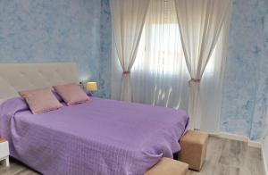 um quarto com uma cama roxa e uma janela em Apartamento Angel em San Fernando