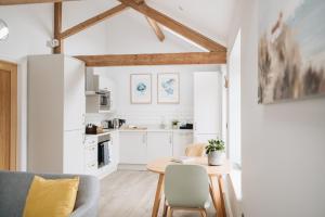 a kitchen with white cabinets and a table and chairs at The Old Granary in Barnetby le Wold