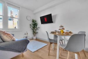 homely - West London Apartments Putney في لندن: غرفة معيشة مع طاولة وتلفزيون على الحائط
