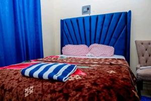 a bed with a blue head board and pillows on it at Ziggon villa mtwapa in Mombasa