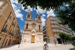 a man riding a bike in front of a church at Santa Lucia Affittacamere in Gioia del Colle