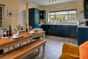 a kitchen with blue cabinets and a wooden table at Finest Retreats - Tan-Y-Dderwen in Aberhafesp