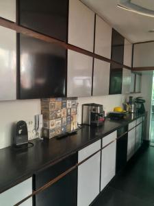 a kitchen with white cabinets and a black counter top at Suíte confortavel in Rio de Janeiro