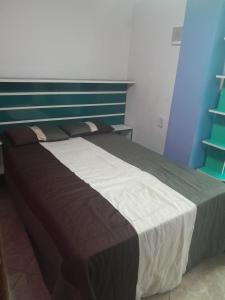 Schlafzimmer mit einem Bett mit einem blauen und weißen Kopfteil in der Unterkunft Suíte confortavel in Rio de Janeiro