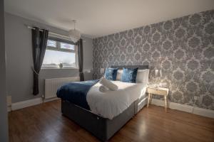 a bedroom with a bed with blue pillows and a window at Pine House By Horizon Stays in Hartlepool