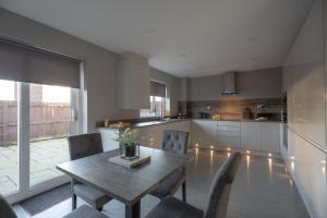 a kitchen and dining room with a wooden table and chairs at Pine House By Horizon Stays in Hartlepool
